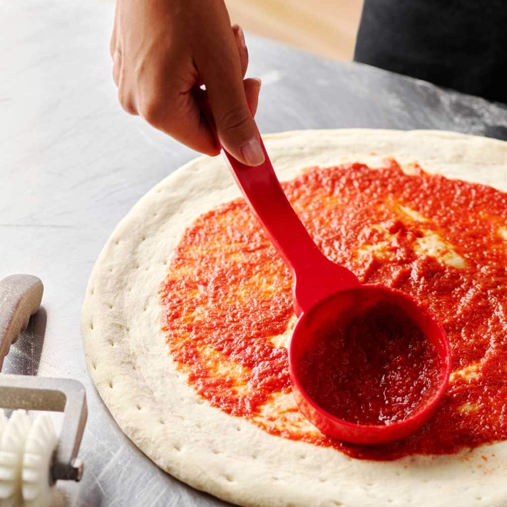 pizza sauce poured onto fresh dough